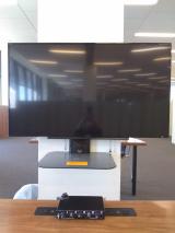 Head on view. A large screen hung on a white column. A half circle table below the screen includes a headphone amp.