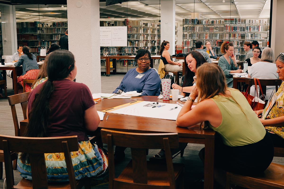 People sit and talk around a table in a library