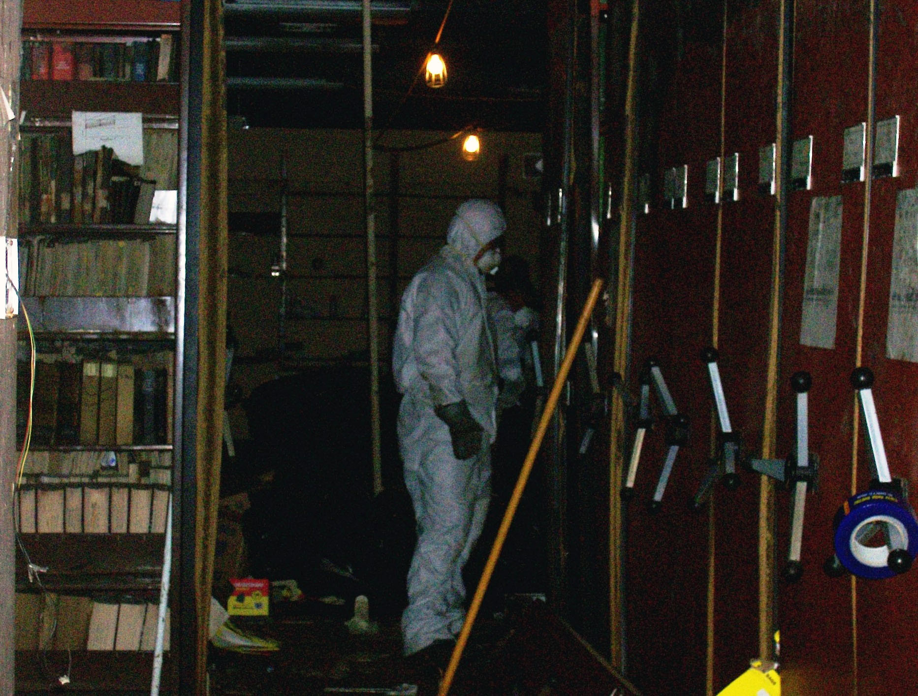 Person in protective personal equipment stands inside a dark library storage
