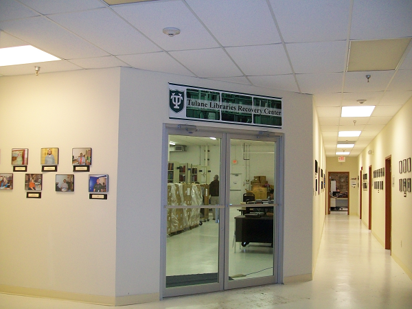 Brightly lit hallway with two metal and glass doors. Over the door a sign reads "Tulane Libraries Recovery Center."