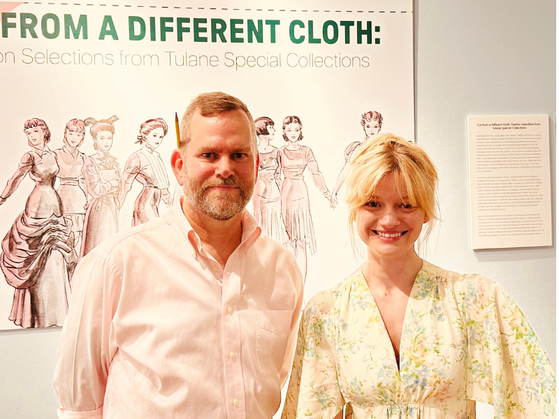 Photo of Faye Daigle and Kevin Williams standing in front of the sign for "Cut from a Different Cloth" exhibit