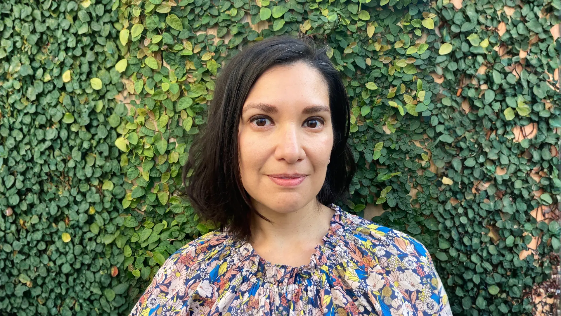 Photo of Jillian Cuellar in front of green, vine covered wall