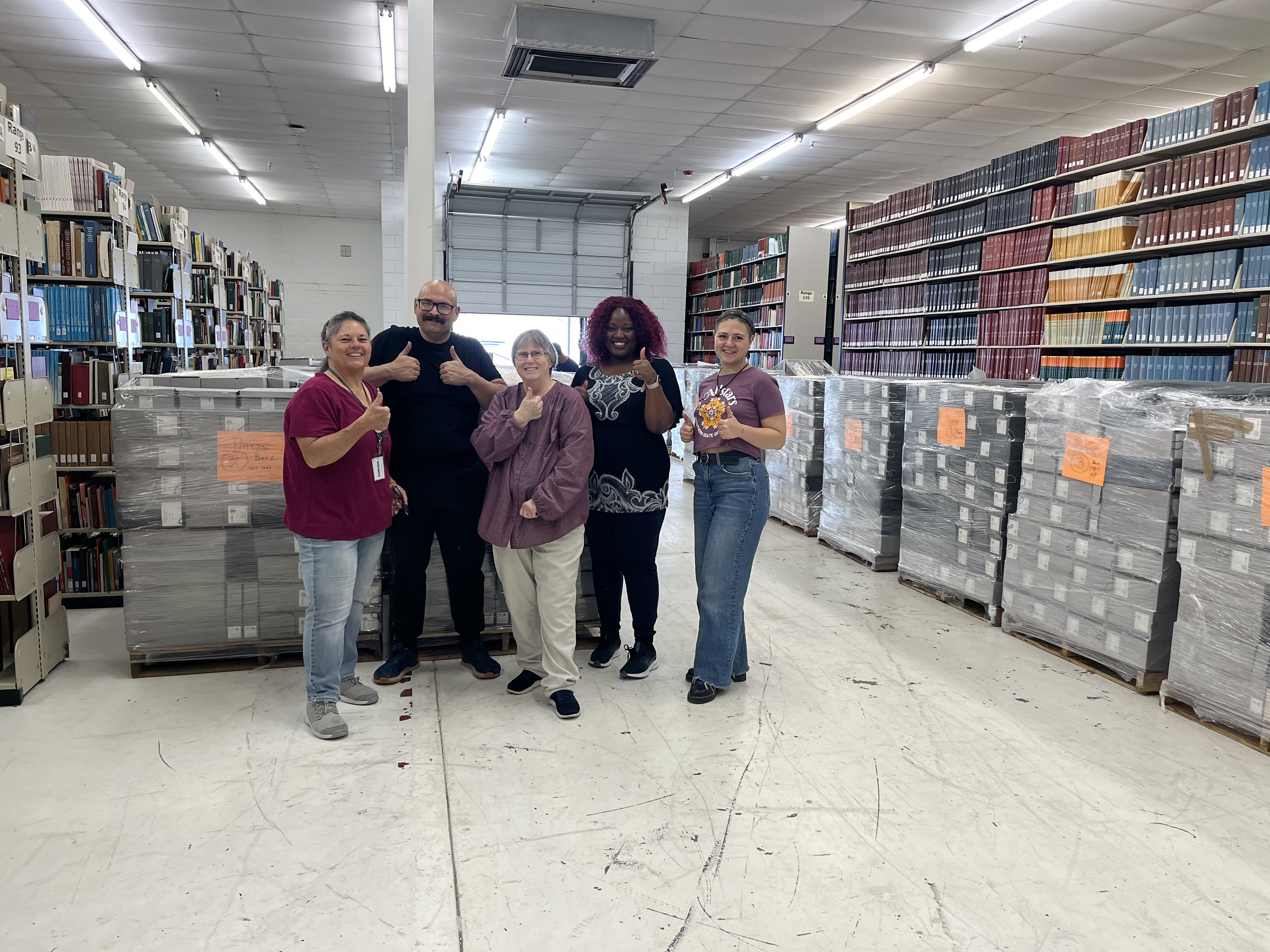 Photo of group of librarians posed with many pallets of document boxes that hold the Gingrich Congressional Collection