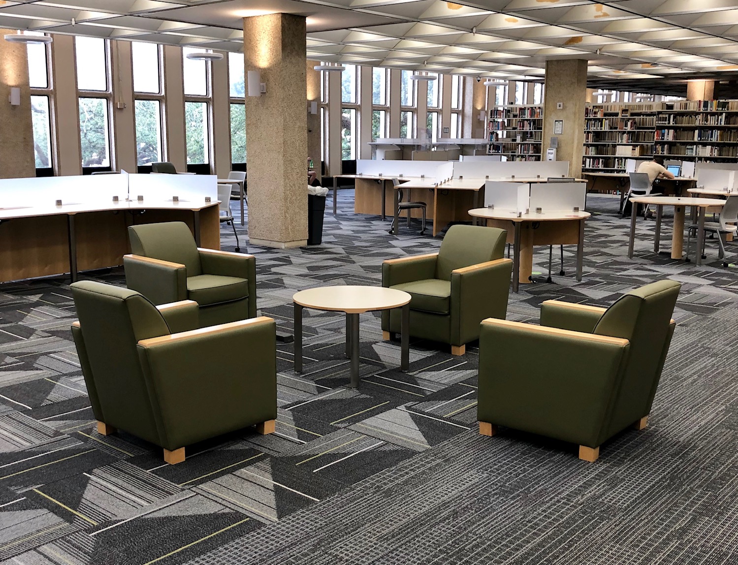 Lounge chair seating as well as work table areas separated by low dividers in the 2nd Floor Study Commons. Narrow windows look out on the front of the building.