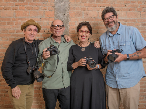 Four people posed with cameras in front of a brick wall