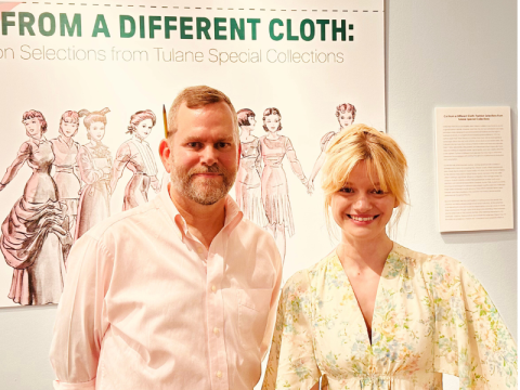 Photo of Faye Daigle and Kevin Williams standing in front of the sign for "Cut from a Different Cloth" exhibit