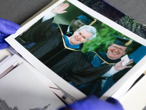 Gloved hands hold a photo of Newt Gingrich